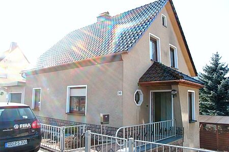 Verblasste Fassade eines Einfamilienhauses mit grauen Schäden im ersten Stock