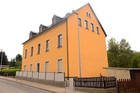 Pastellgelbes Mehrfamilienhaus an einer Straße