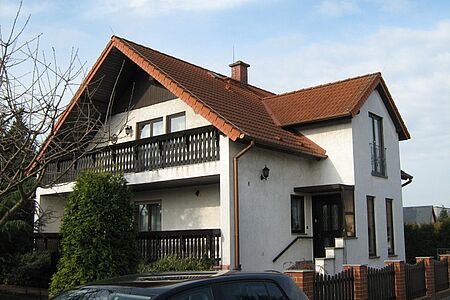Zweifamilienhaus mit Holzbalkon vor der Fassadensanierung