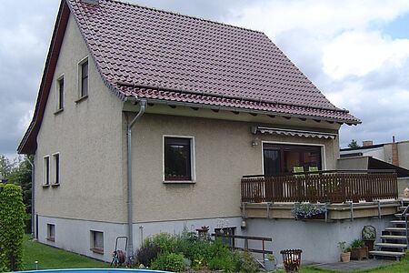 Beiges Einfamilienhaus mit hellgrauem Fundament und leicht veralteter Fassade vor der Sanierung