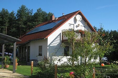 Weißes Einfamilienhaus mit Holzbalkon vor der Sanierung