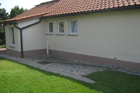 Bungalow mit flachem Satteldach und schmutzig-weißer Fassade