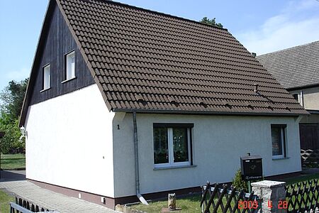 Weißes Einfamilienhaus mit schwarzer Holzvertäfelung im Dachgeschoss