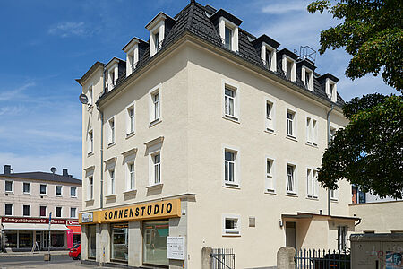 Zweifamilienhaus mit helloranger Fassade und weißem Querstreifen sowie roten Dachziegeln