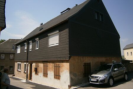 Mehrfamilienhaus mit unebenmäßigem Putz im Erdgeschoss