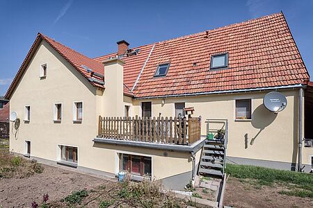 Großes, verwinkeltes Wohnhaus mit ebenmäßiger, eierschalenfarbener Fassade
