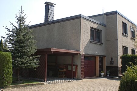 Haus mit Flachdach und alter, grauer Fassade