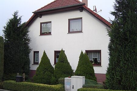 Wohnhaus mit weißer Fassade und Krüppelwalmdach