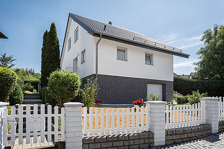 Einfamilienhaus mit strahlend weißer Fassade und grau verklinkertem Untergeschoss
