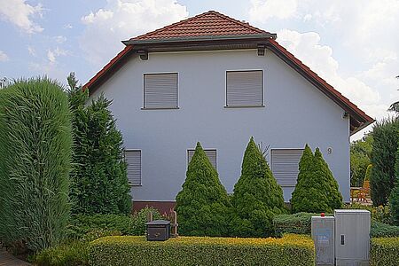 Wohnhaus mit hellblauer Fassade und Krüppelwalmdach