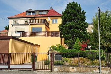 Mehrstöckiges Wohnhaus mit Walmdach und Fassade in Orange und Weiß