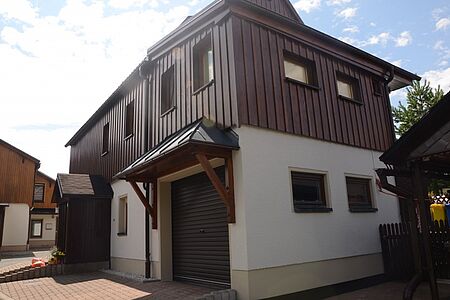 Traditionelles Haus mit weißer Fassade und Holzverkleidung ab erster Etage