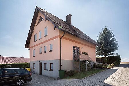 Wohnhaus mit grauem Fundament und korallefarbener Fassade