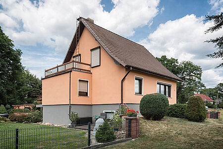Einfamilienhaus mit Fassade in knalligem Korallenorange und grauem Kellergeschoss
