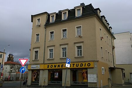 Hellgelbes Zweifamilienhaus mit schwarzen Dachziegeln