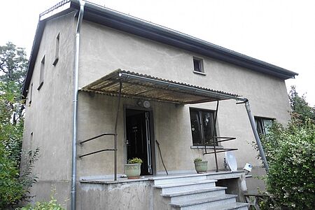 Graubraun verputztes Wohnhaus mit Treppenaufgang ohne Geländer