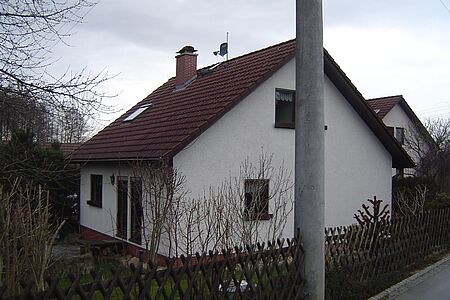 Kleines, weißes Einfamilienhaus mit leicht veralteter Fassadenbeschichtung