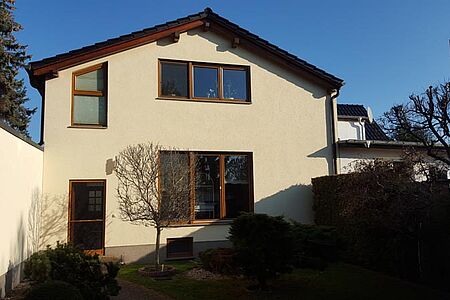 Hellbeiges Wohnhaus mit großen Fenstern