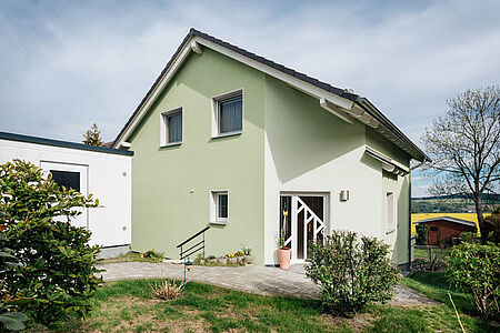 Hellgrünes Einfamilienhaus mit frischer, ebenmäßiger Fassade