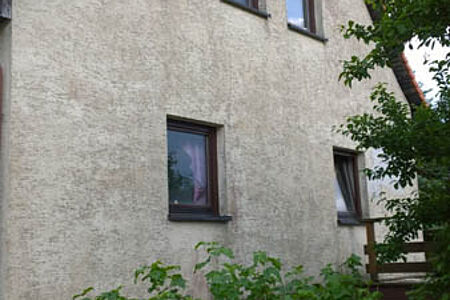 Verputztes Einfamilienhaus mit Witterungsspuren auf der Fassade