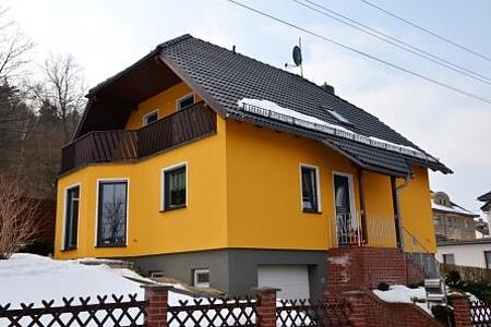 Oranges Wohnhaus mit drei Stockwerken, Erkerfenstern und Balkon