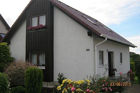 Wohnhaus mit leicht verschmutzter, weißer Fassade und vertäfelten Elementen