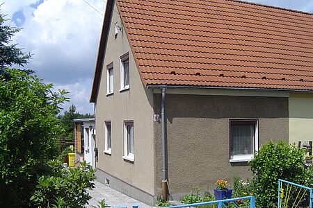 Grau verputztes Doppelhaus vor der Fassadensanierung