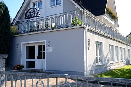 Großes hellblaues Haus mit mehreren Balkonen und schmiedeeisernem Geländer