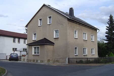 Graues Mehrfamilienhaus mit kleinem Vorbau