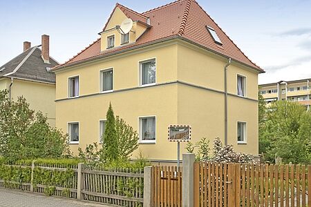 Villa mit Walmdach und frisch gestrichener Fassade in Gelb