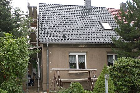 Kleines Haus mit brauner Fassade bei der Sanierung mit einzelnen Gerüsten