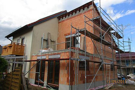 Wohnhaus mit Anbau im Rohbau während Fassadenarbeiten mit Gerüst