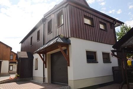 Eckansicht von Einfamilienhaus mit weißer Fassade und Garage im Vordergrund