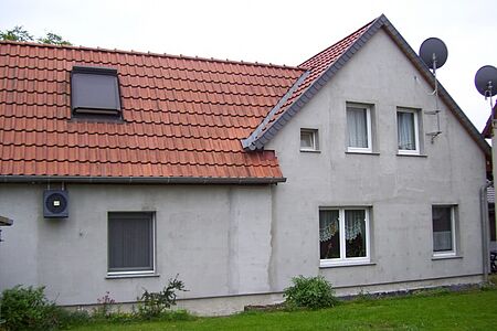 Haus mit fleckiger Fassade in hellem Grau
