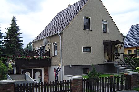 Hellgrau verputztes Einfamilienhaus ohne Anstrich