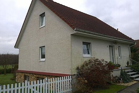 Beige verputztes Einfamilienhaus mit sanierungsbedürftiger Fassade