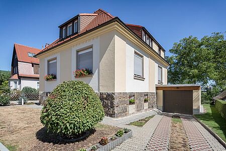 Hellgelbes Wohnhaus mit Walmdach und weiß umrahmten Fenstern
