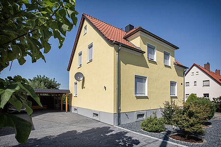 Mehrstöckiges Wohnhaus mit ebenmäßiger Fassade in hellem Gelb