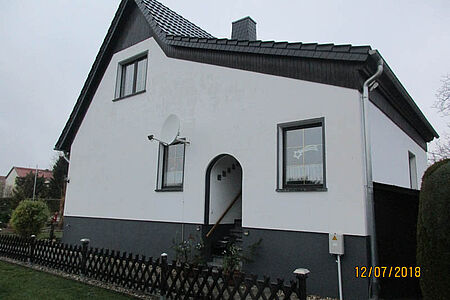 Wohnhaus mit verschmutzten, weißen Fassadenelementen 