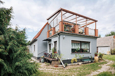 Blaugraues Wohnhaus mit verglastem Balkon