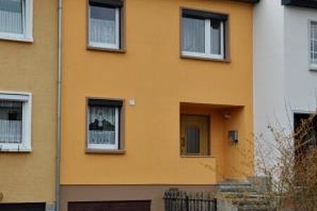 Schmales Reihenhaus mit oranger Fassade nach der Sanierung