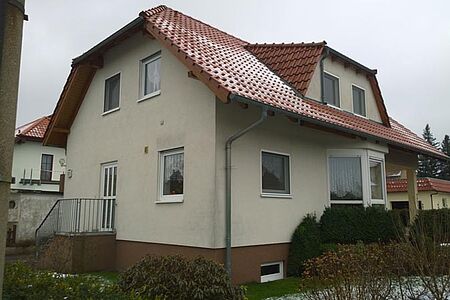 Einfamilienhaus mit Krüppelwalmdach und verschmutzter Fassade