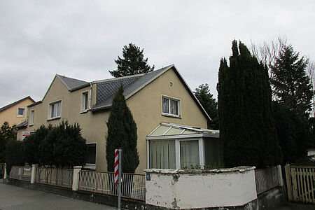 Großes Wohnhaus mit leicht verschmutzter Fassade in einem hellen Gelbton