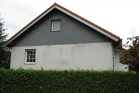 Haus mit schmutziger, weißer Fassade und Vertäfelung