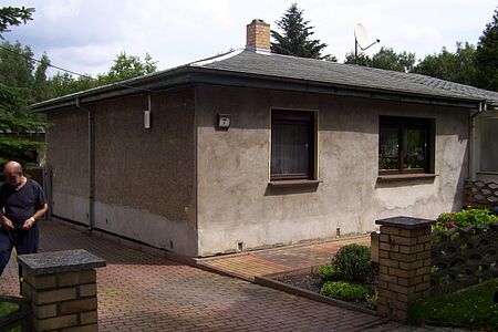 Bungalow mit fleckiger Fassade in verschiedenen Grautönen