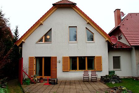Weißes Wohnhaus im Grünen mit verschmutzter Fassade