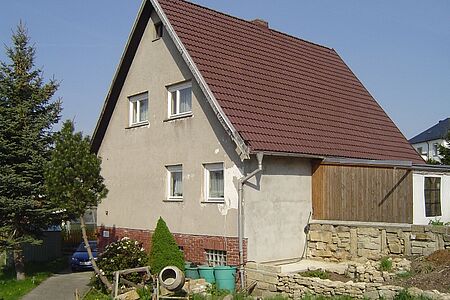 Einfamilienhaus mit bröckelnder, grauer Fassade