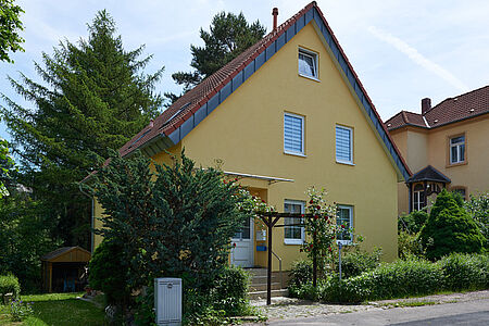 Sonnig gelbes Wohnhaus nach der Fassadensanierung