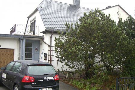Weißes Haus mit schwarzem Auto vor dem Garagentor