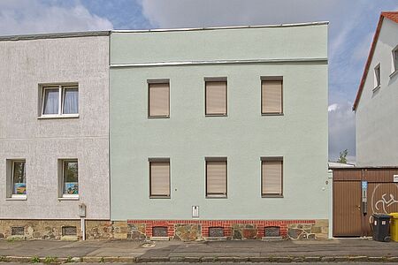 Mintgrünes Haus mit Flachdach nach der Fassadensanierung